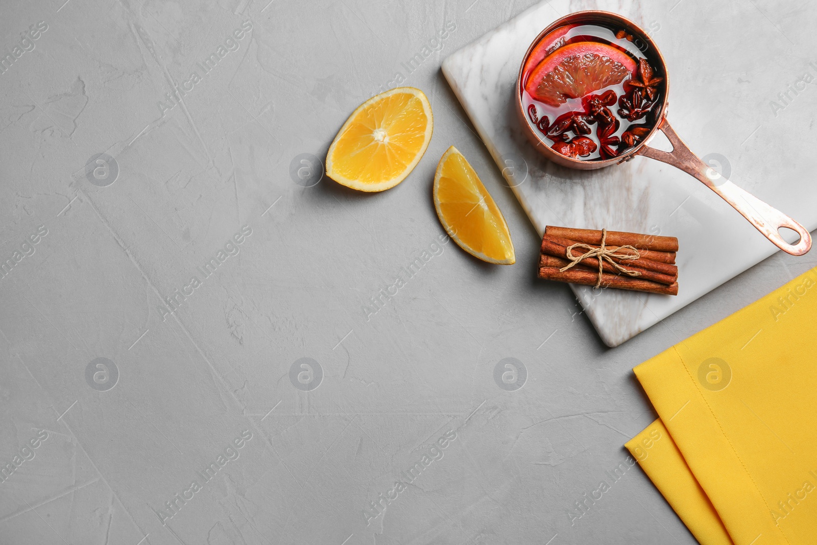 Photo of Flat lay composition with saucepan of hot mulled wine and space for text on gray background