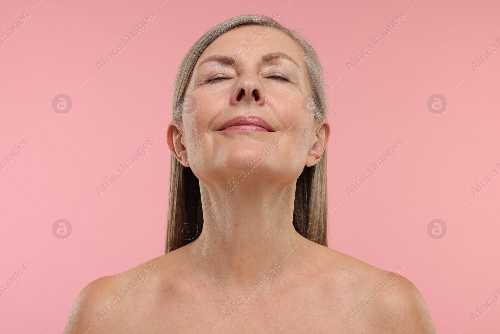 Photo of Beautiful woman showing her neck on pink background