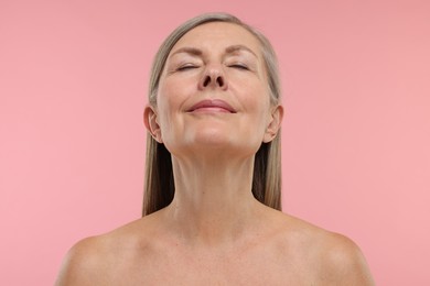 Beautiful woman showing her neck on pink background