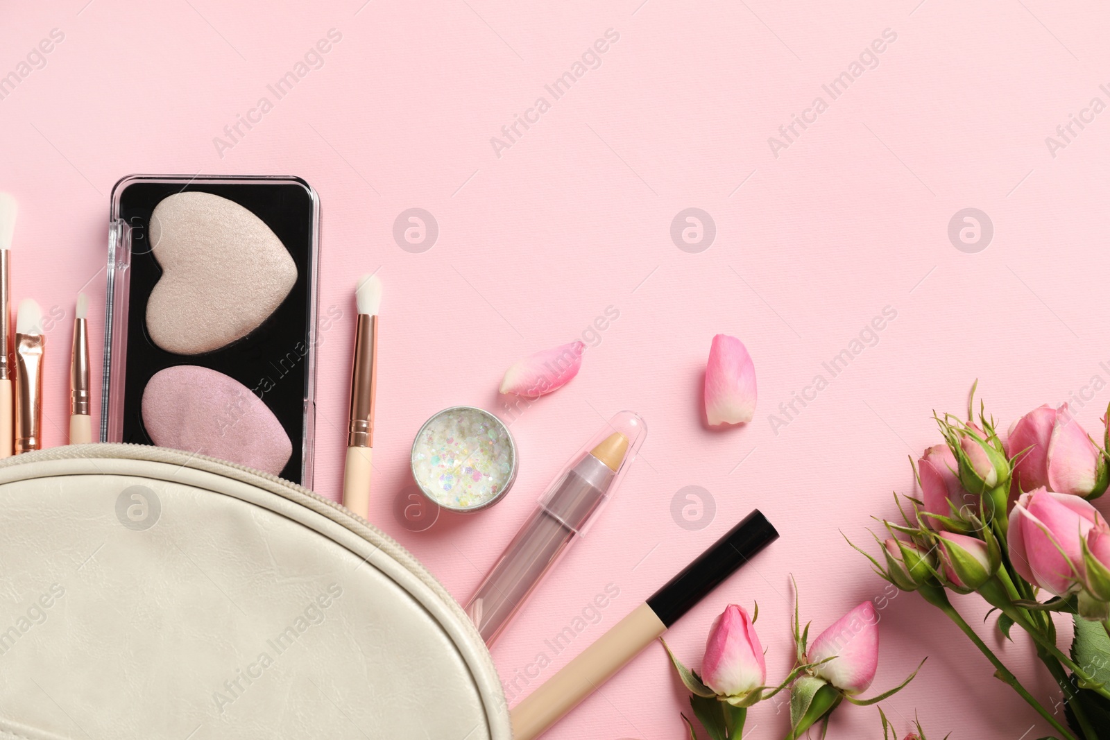 Photo of Set of makeup products with bag and roses on light pink background, flat lay. Space for text