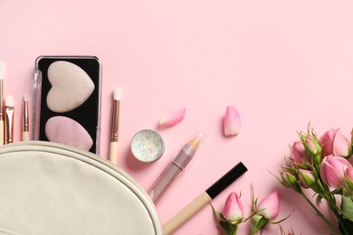 Photo of Set of makeup products with bag and roses on light pink background, flat lay. Space for text