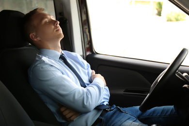 Photo of Tired young man sleeping in his modern car