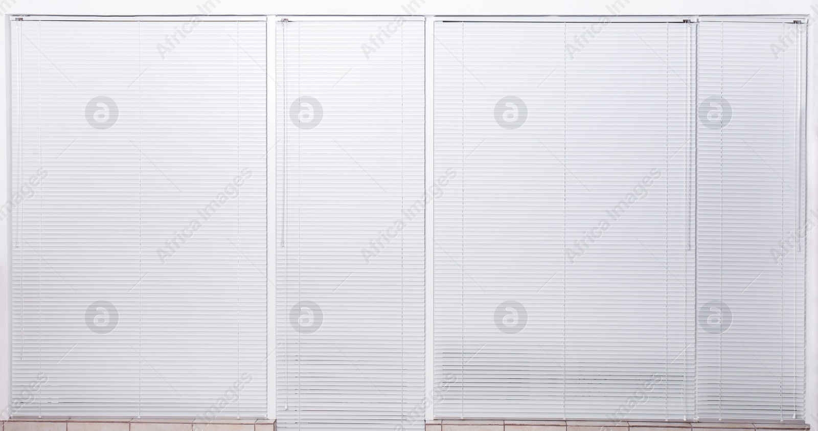 Photo of Windows with closed white horizontal blinds indoors