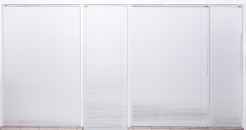 Windows with closed white horizontal blinds indoors