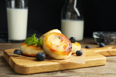 Photo of Delicious cottage cheese pancakes with blueberries and mint on wooden table