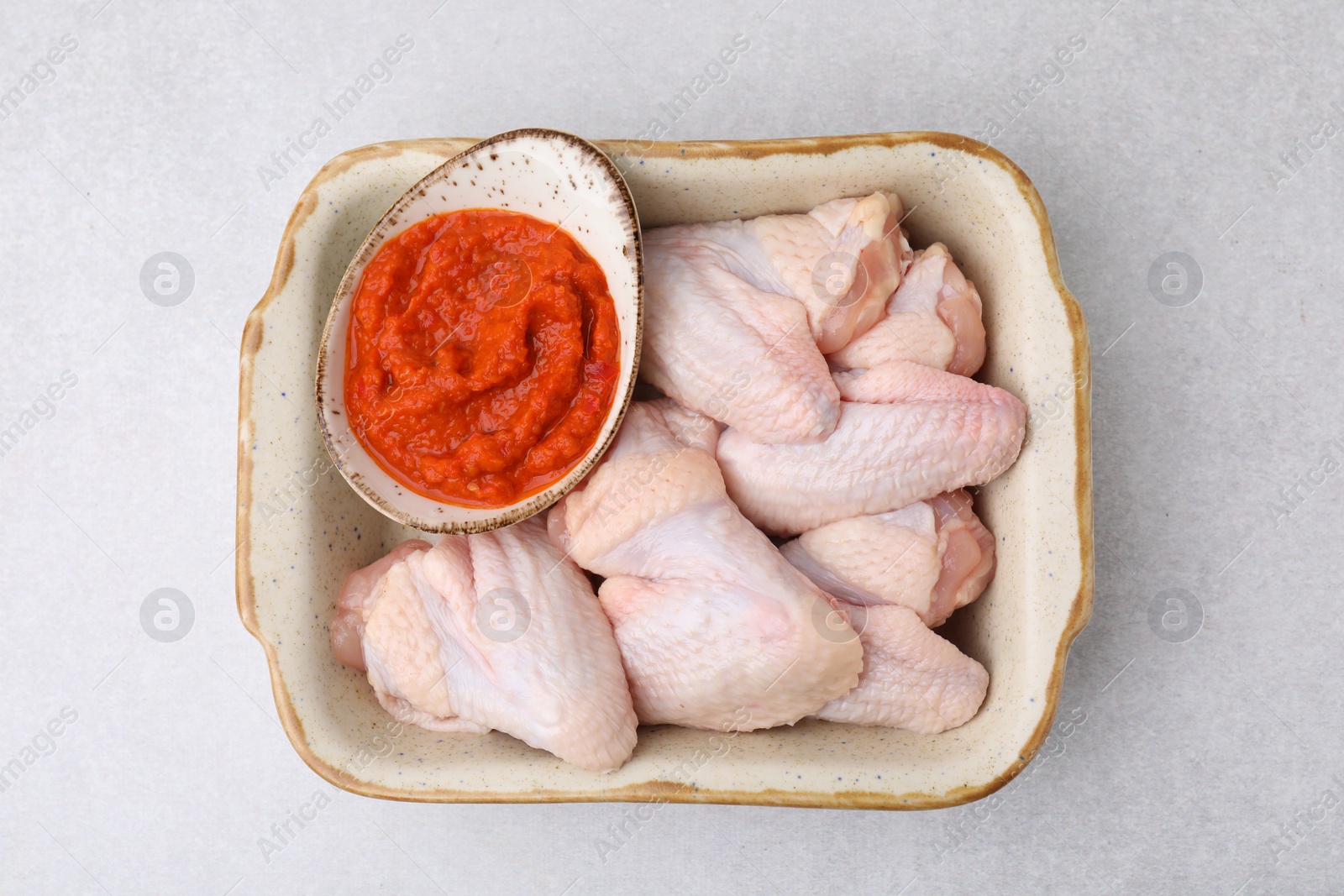 Photo of Fresh marinade and raw chicken in baking dish on light table, top view