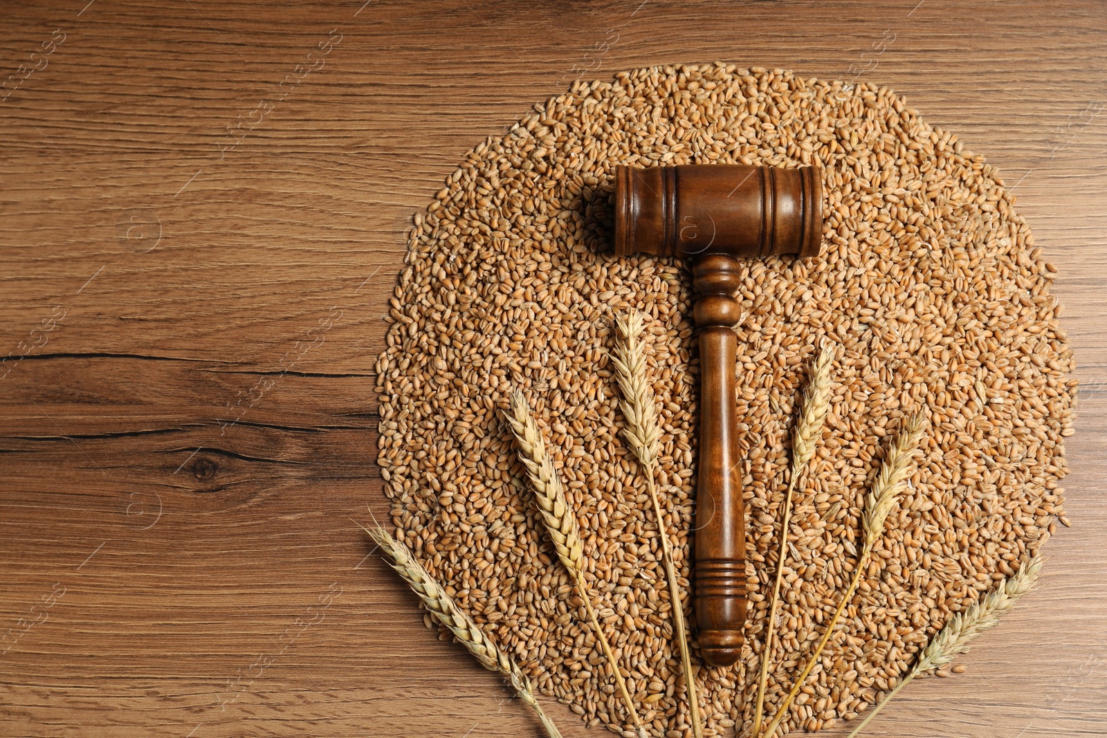 Photo of Agricultural deal. Judge's gavel, wheat ears and grains on wooden table, top view. Space for text