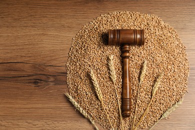 Photo of Agricultural deal. Judge's gavel, wheat ears and grains on wooden table, top view. Space for text