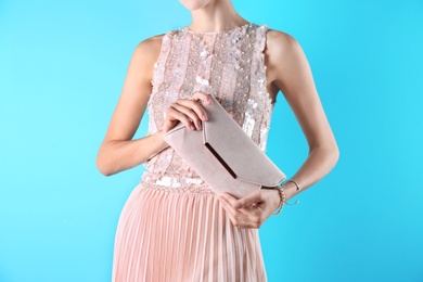 Young woman in stylish outfit with purse on color background, closeup