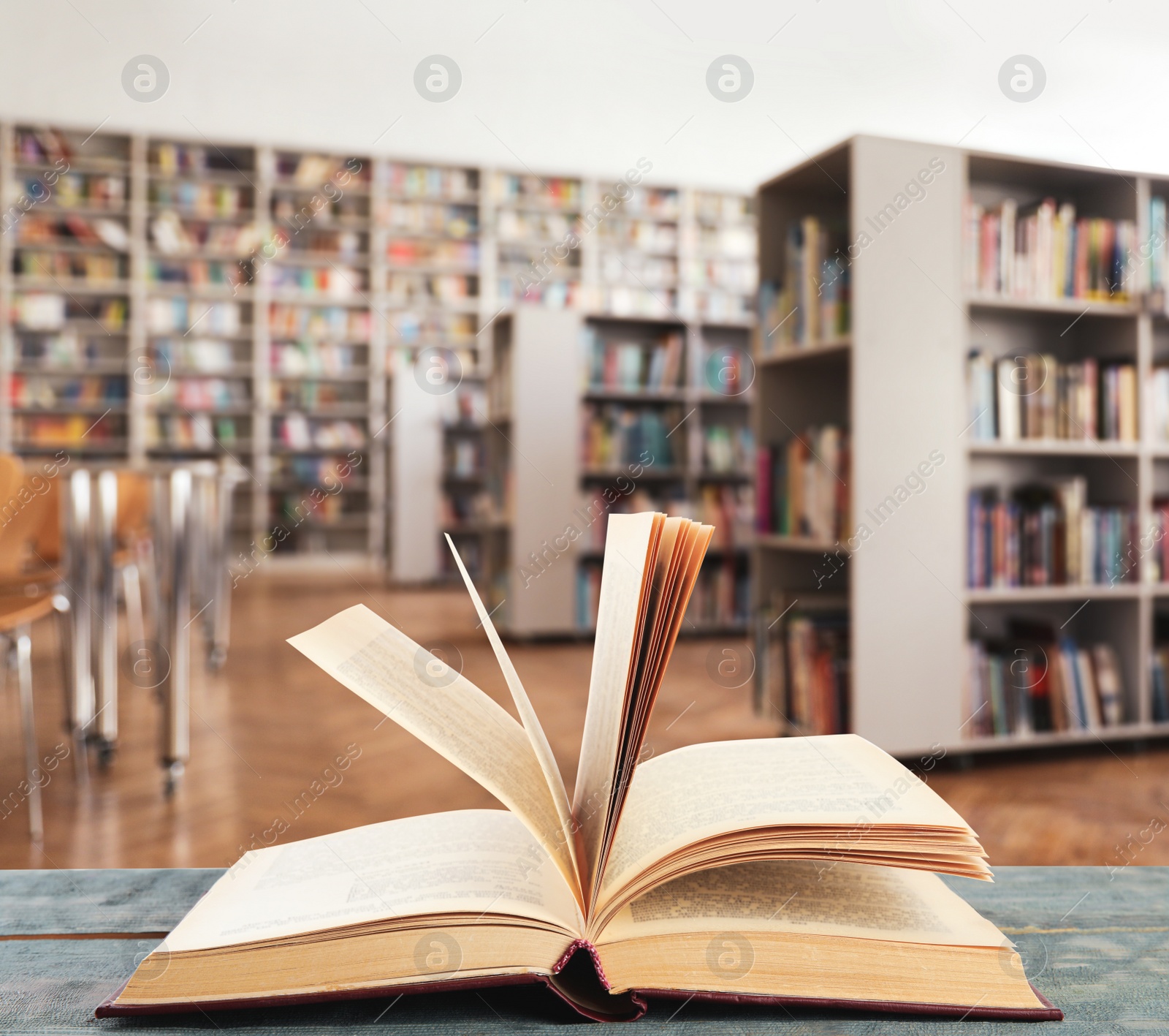 Image of Open hardcover book on wooden table in library