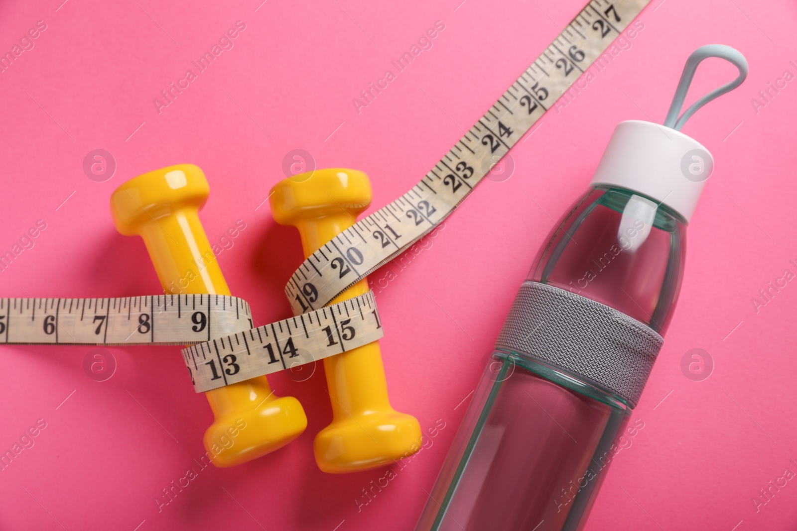 Photo of Measuring tape, bottle of water and dumbbells on pink background, flat lay. Weight control concept
