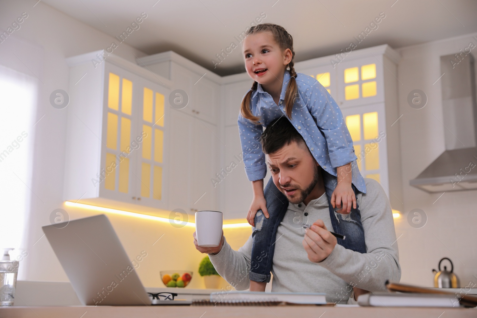 Photo of Overwhelmed man combining parenting and work at home