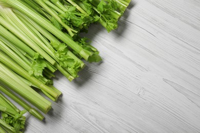Fresh ripe green celery on white wooden table, flat lay. Space for text