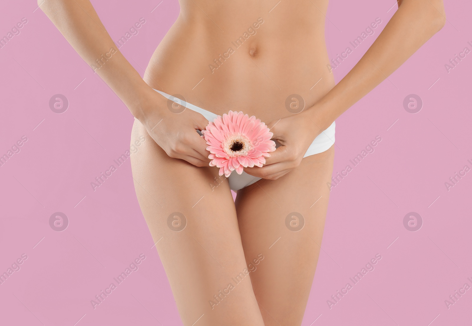 Photo of Woman with flower showing smooth skin after bikini epilation on pink background, closeup. Body care concept