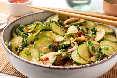 Photo of Bowl of delicious cucumber salad served on table, closeup