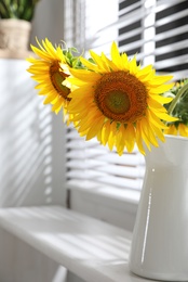 Bouquet of beautiful sunflowers in vase near window at home