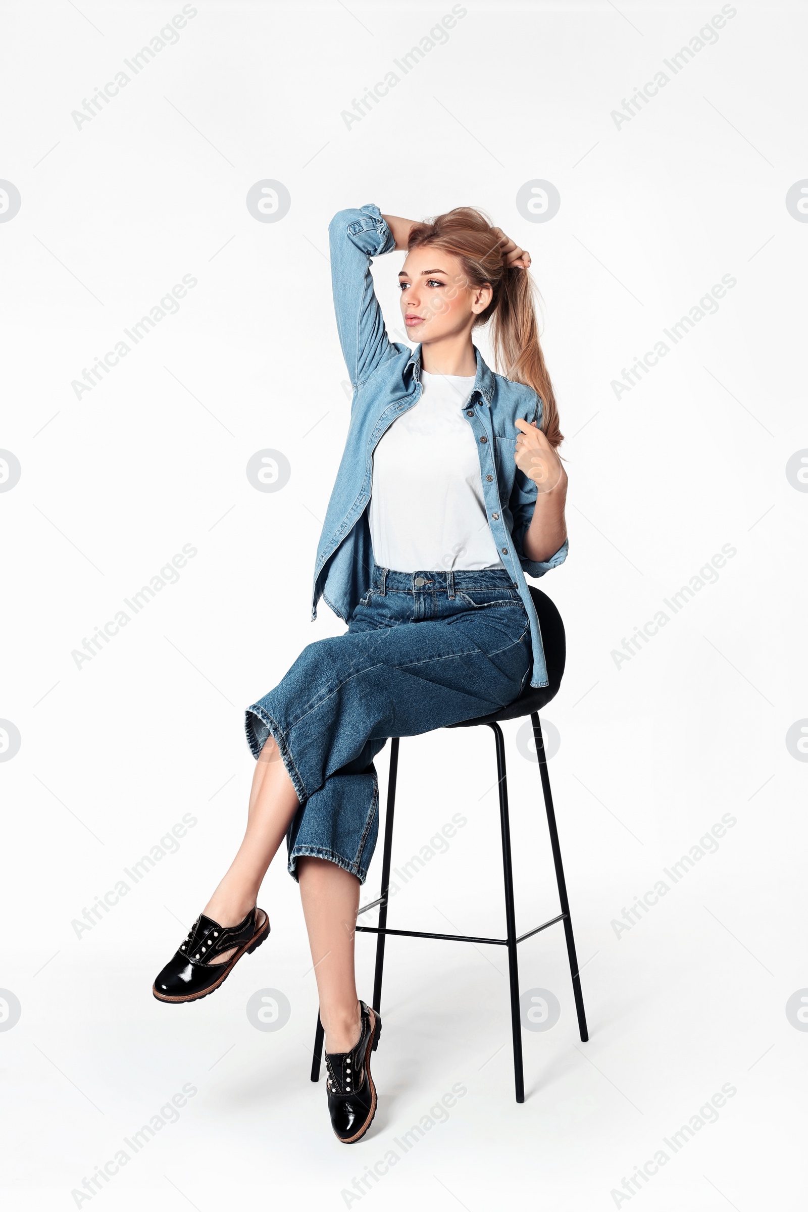 Photo of Full length portrait of woman in stylish shoes on stool against white background