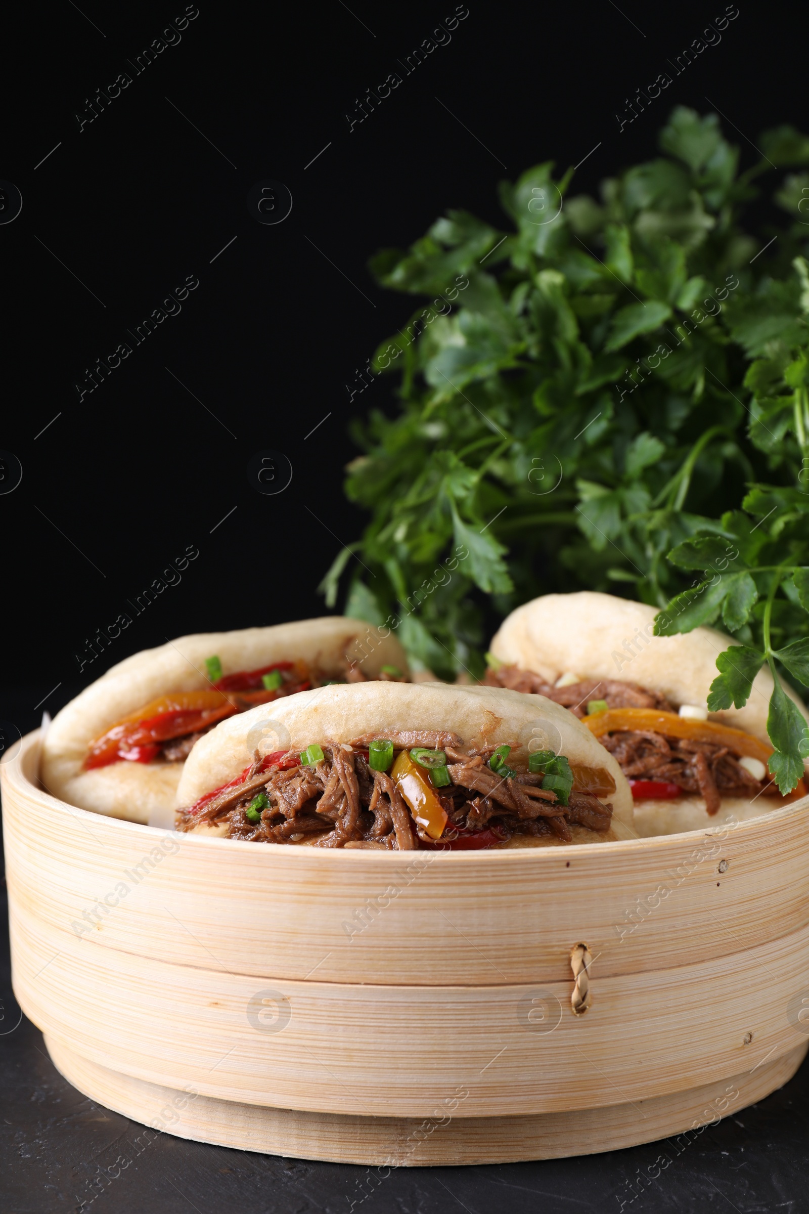 Photo of Delicious gua bao in bamboo steamer on black table