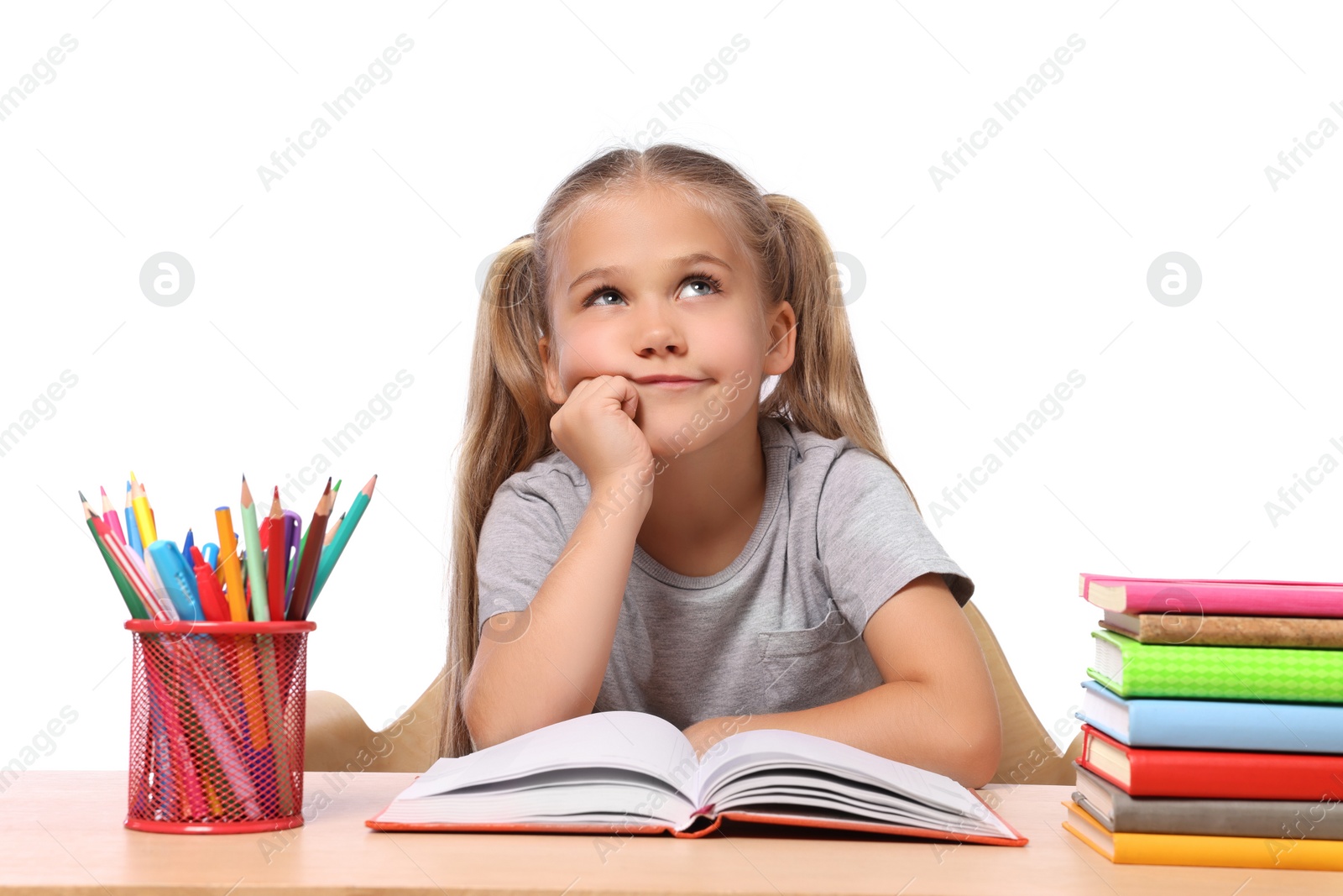 Photo of Little girl with stationery and books suffering from dyslexia at wooden table