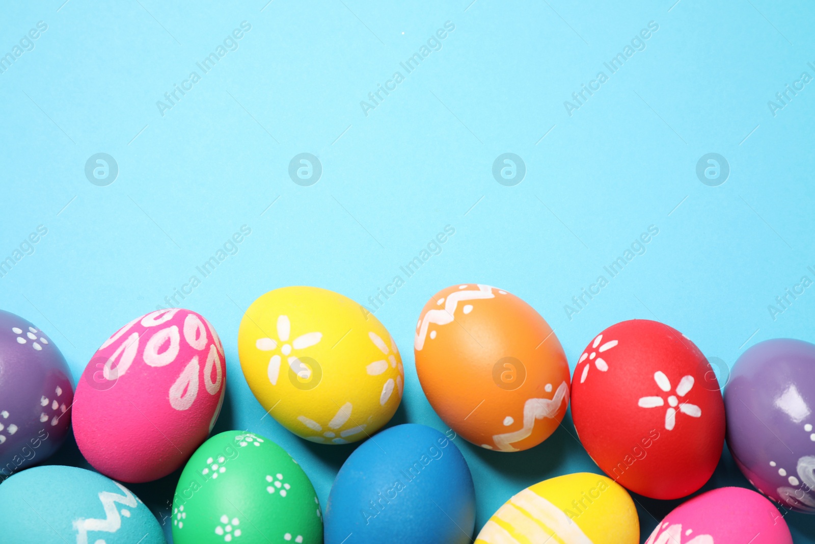 Photo of Colorful Easter eggs on light blue background, flat lay. Space for text