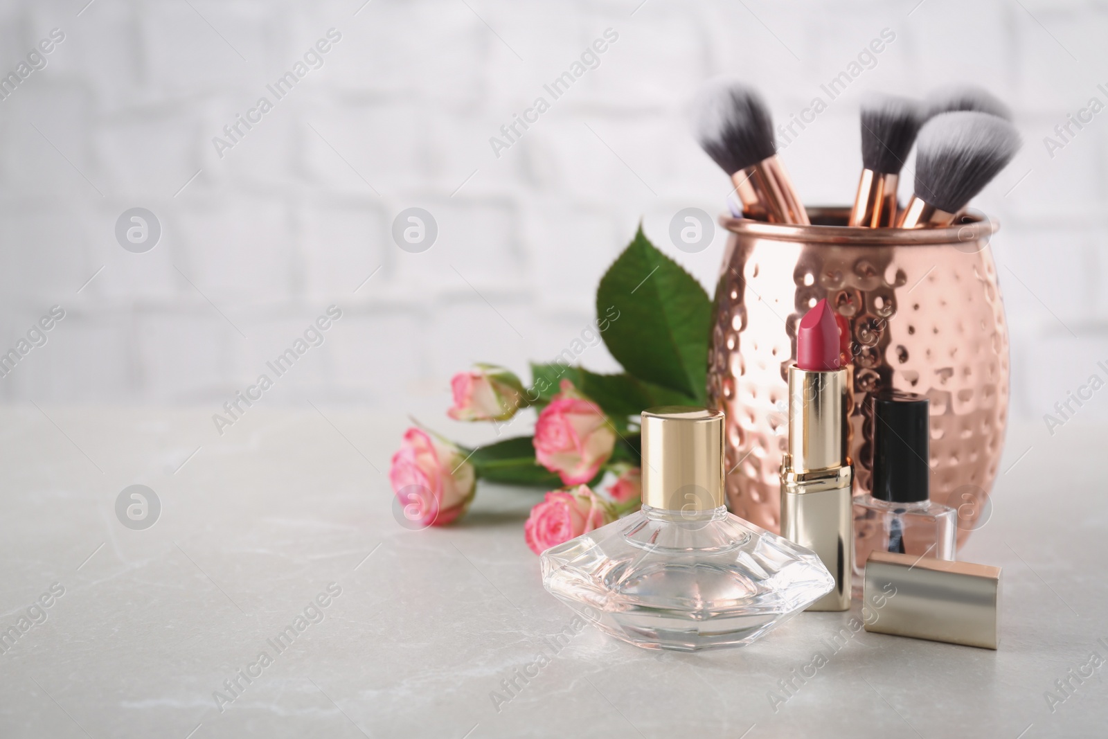 Photo of Beautiful composition with lipstick, perfume and nail polish on light table, space for text