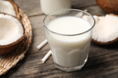 Photo of Glass of delicious vegan milk and coconuts on wooden table, closeup