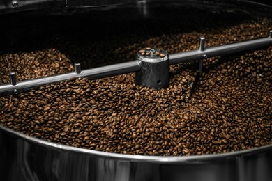 Photo of Modern coffee roaster machine with beans, closeup