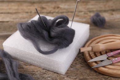 Photo of Felting tools and wool on wooden table, closeup