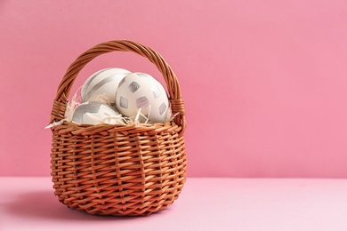 Photo of Basket of Easter eggs on table against color background. Space for text