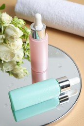 Photo of Bottles of cosmetic products and mirror on beige table