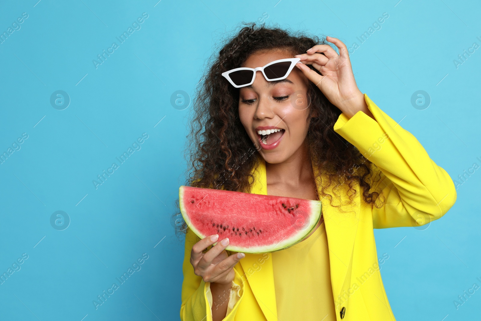 Photo of Beautiful young African American woman with watermelon on light blue background. Space for text