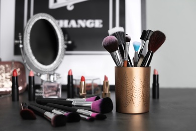 Photo of Makeup products and brushes on grey table
