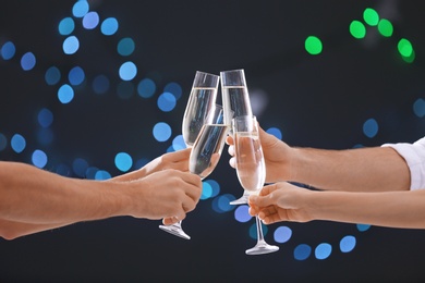 Photo of Friends clinking glasses with champagne on blurred background, closeup