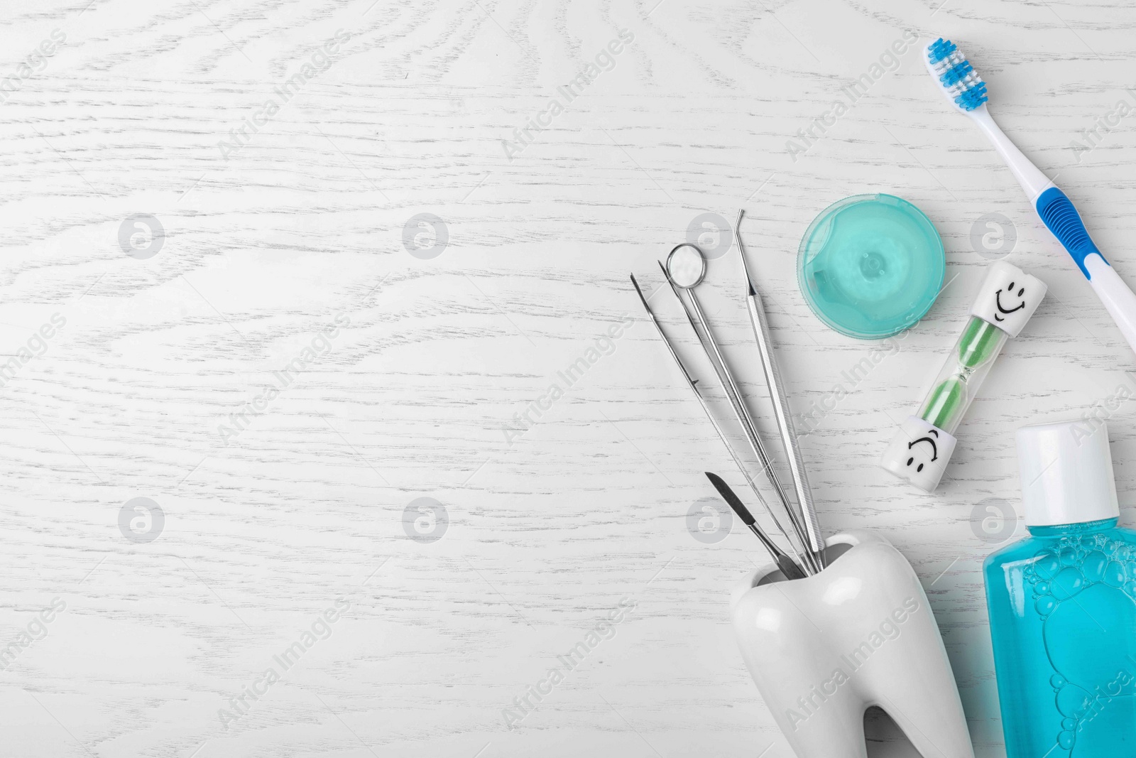 Photo of Flat lay composition with dentist tools and teeth care objects on wooden background. Space for text