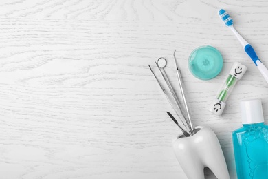 Photo of Flat lay composition with dentist tools and teeth care objects on wooden background. Space for text
