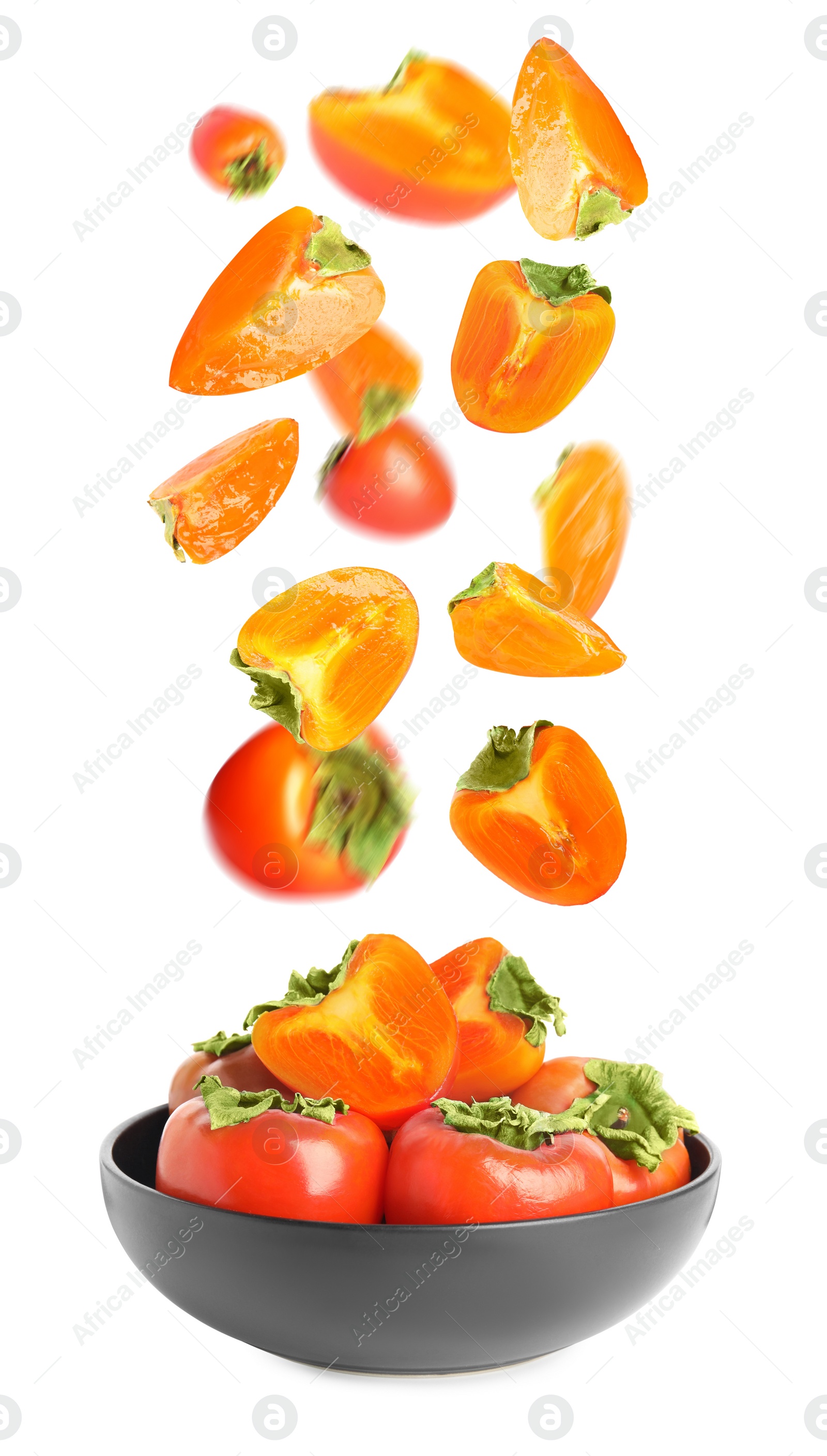 Image of Sweet ripe persimmons falling into bowl on white background