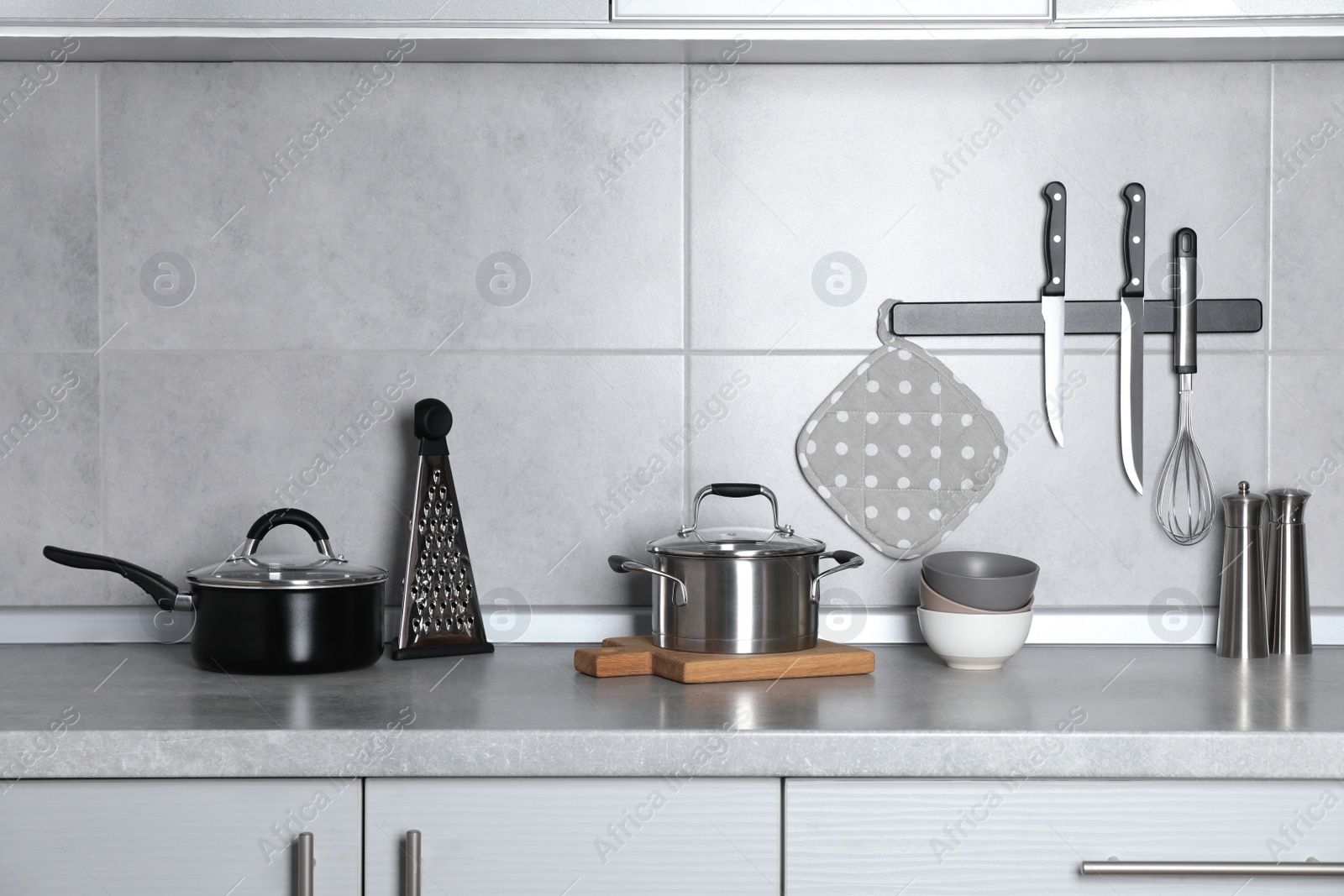 Photo of Set of cooking utensils and cookware on grey countertop