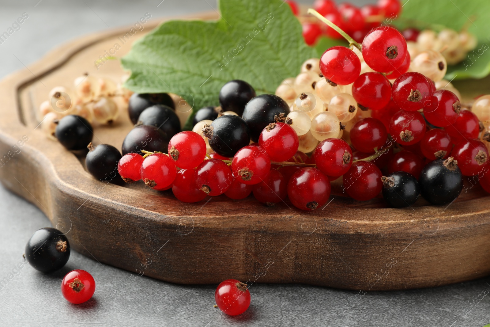 Photo of Different fresh ripe currants and green leaf on table, closeup