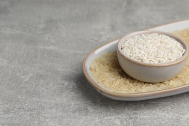 Photo of Different sorts of rice on grey table. Space for text