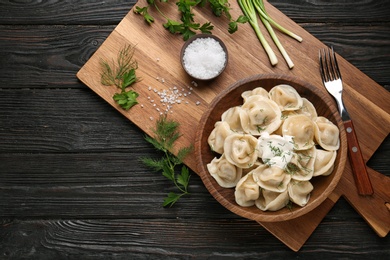 Photo of Flat lay composition with tasty dumplings on black wooden table