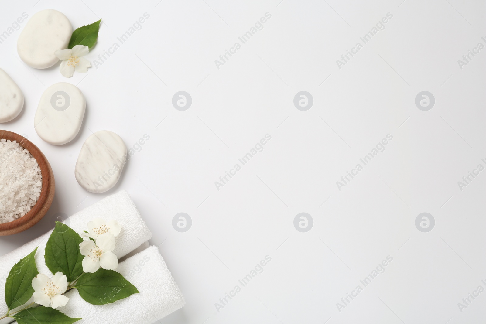 Photo of Spa stones, beautiful jasmine flowers, sea salt and towels on white background, flat lay. Space for text