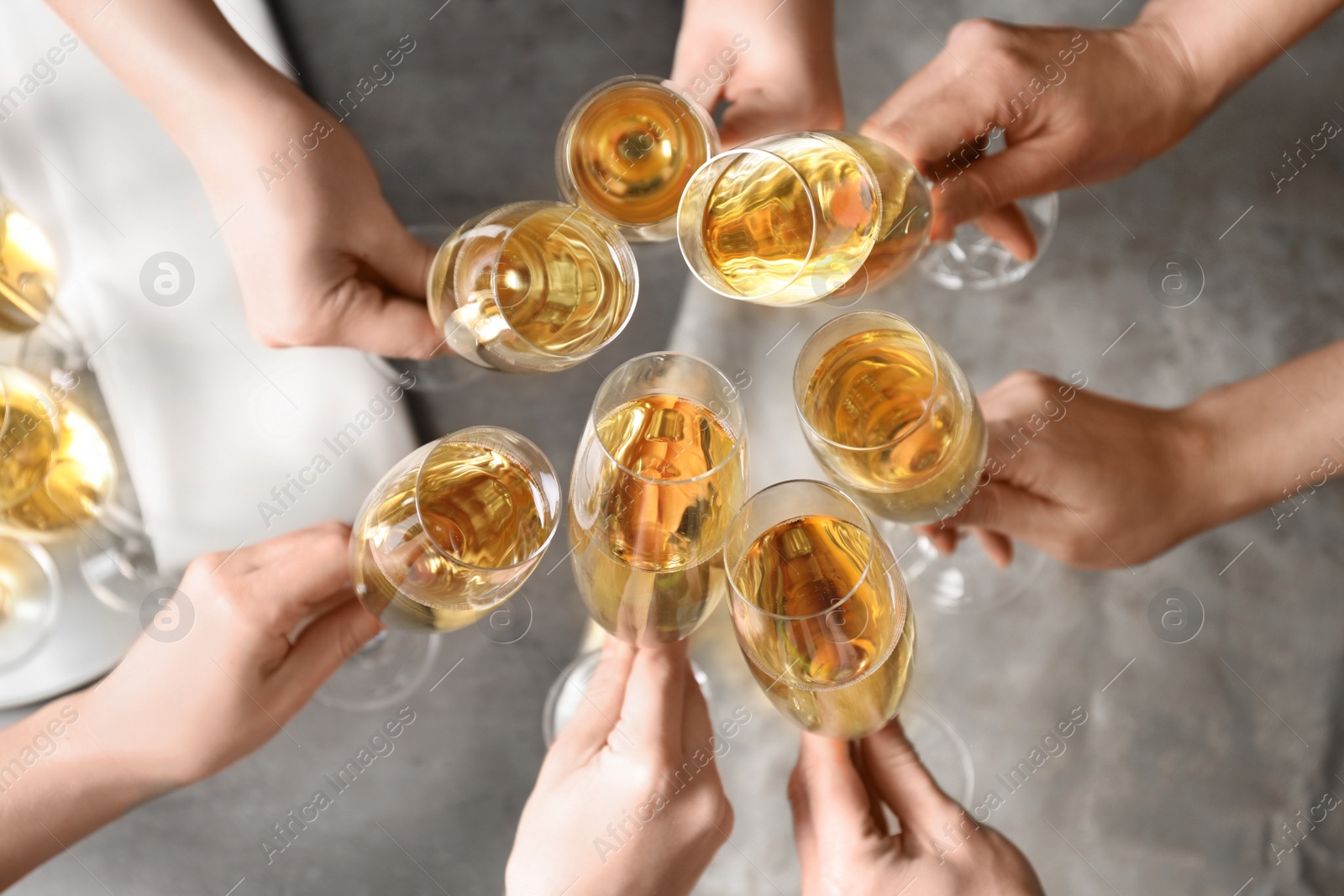 Photo of People clinking glasses with champagne over table, top view