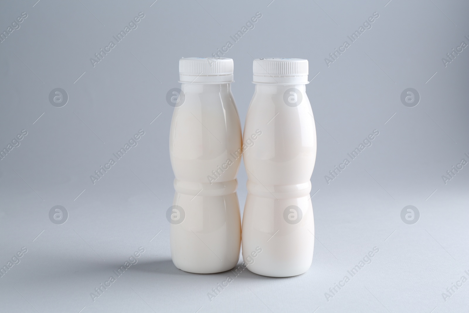 Photo of Tasty yogurt in bottles on light grey background