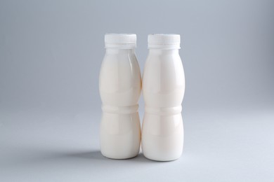 Tasty yogurt in bottles on light grey background