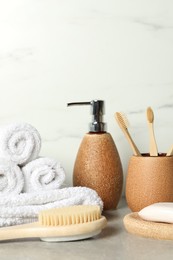 Photo of Different bath accessories and personal care products on gray table near white marble wall