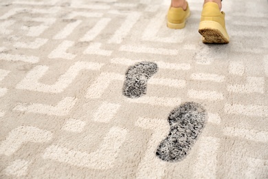 Photo of Person in dirty shoes leaving muddy footprints on carpet