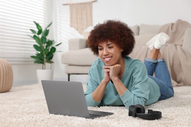 Photo of Beautiful young woman using laptop in room