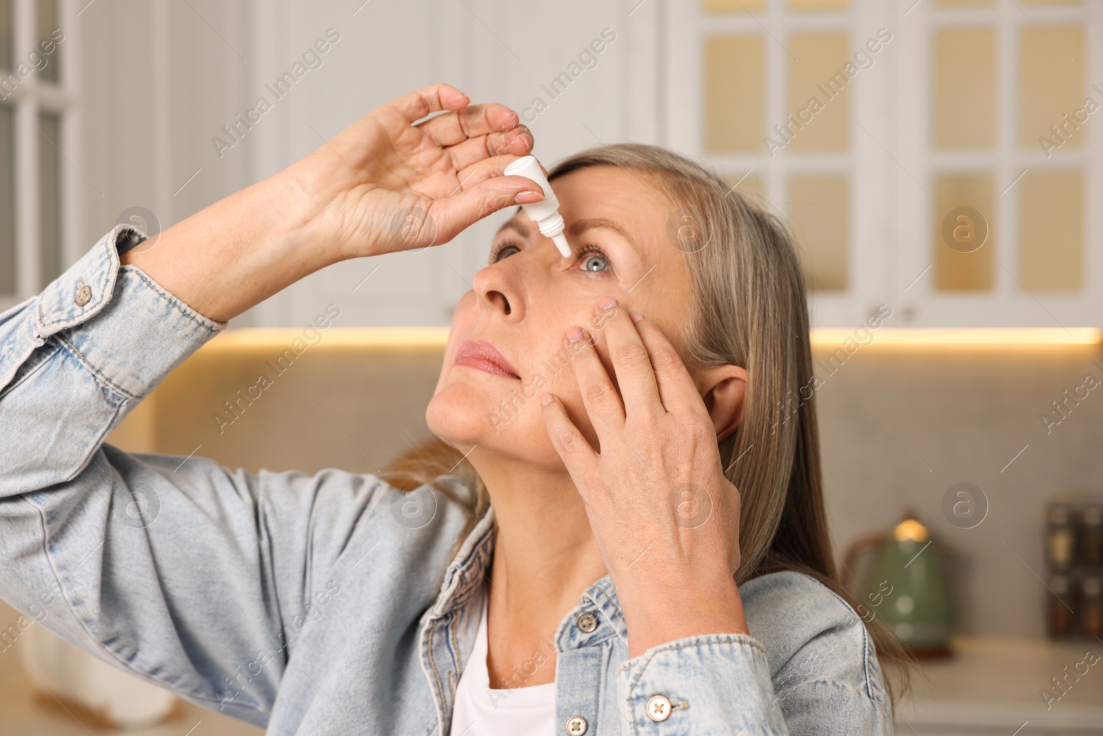 Photo of Woman applying medical eye drops at home