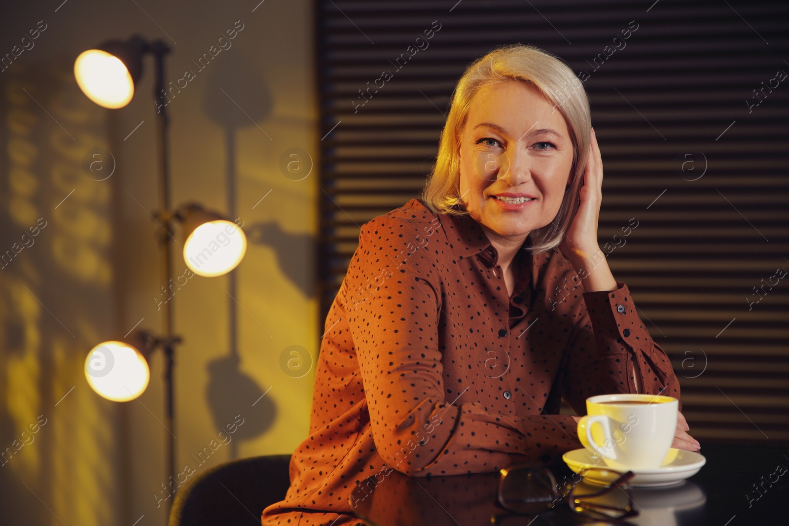 Photo of Beautiful mature woman with cup of coffee indoors. Space for text