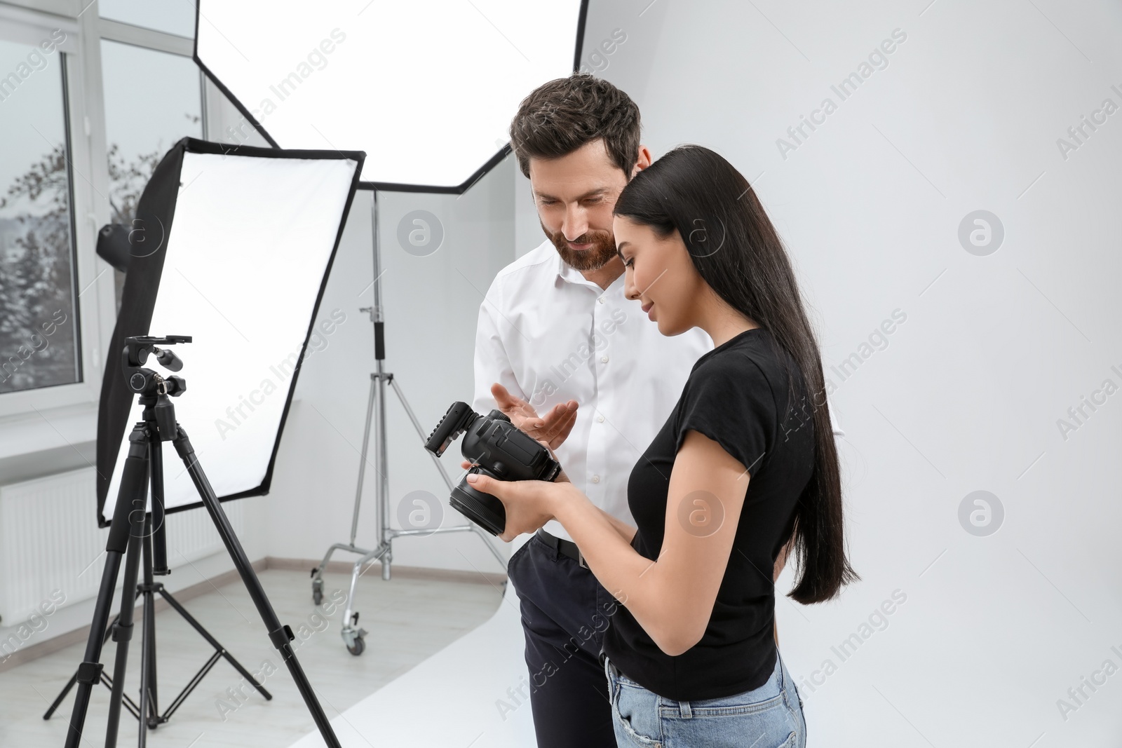 Photo of Professional photographer and model looking at pictures on camera in modern studio